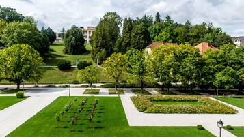 Ein gepflegter Park mit geschnittenen Rasenflächen, verschiedenen Bäumen und einem gut ausgebauten Weg.