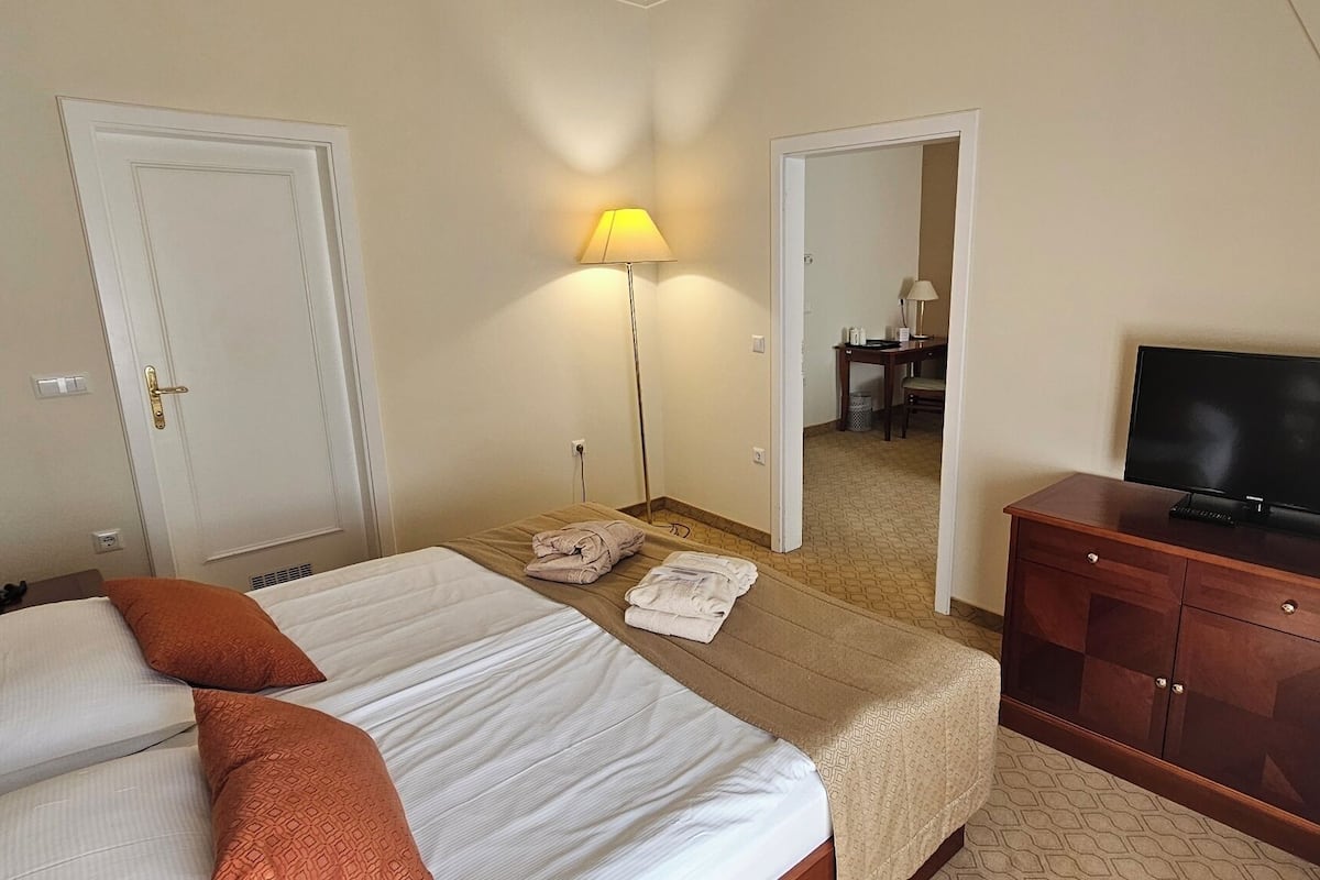 Ein Hotelzimmer mit einem Bett, einem Fernseher auf einer Holzkommode und einer Lampe.