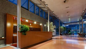 A spacious lobby with a reception desk, large windows, and a modern interior design.