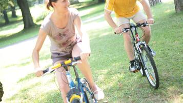 Two people riding bicycles on a grassy path in a park.