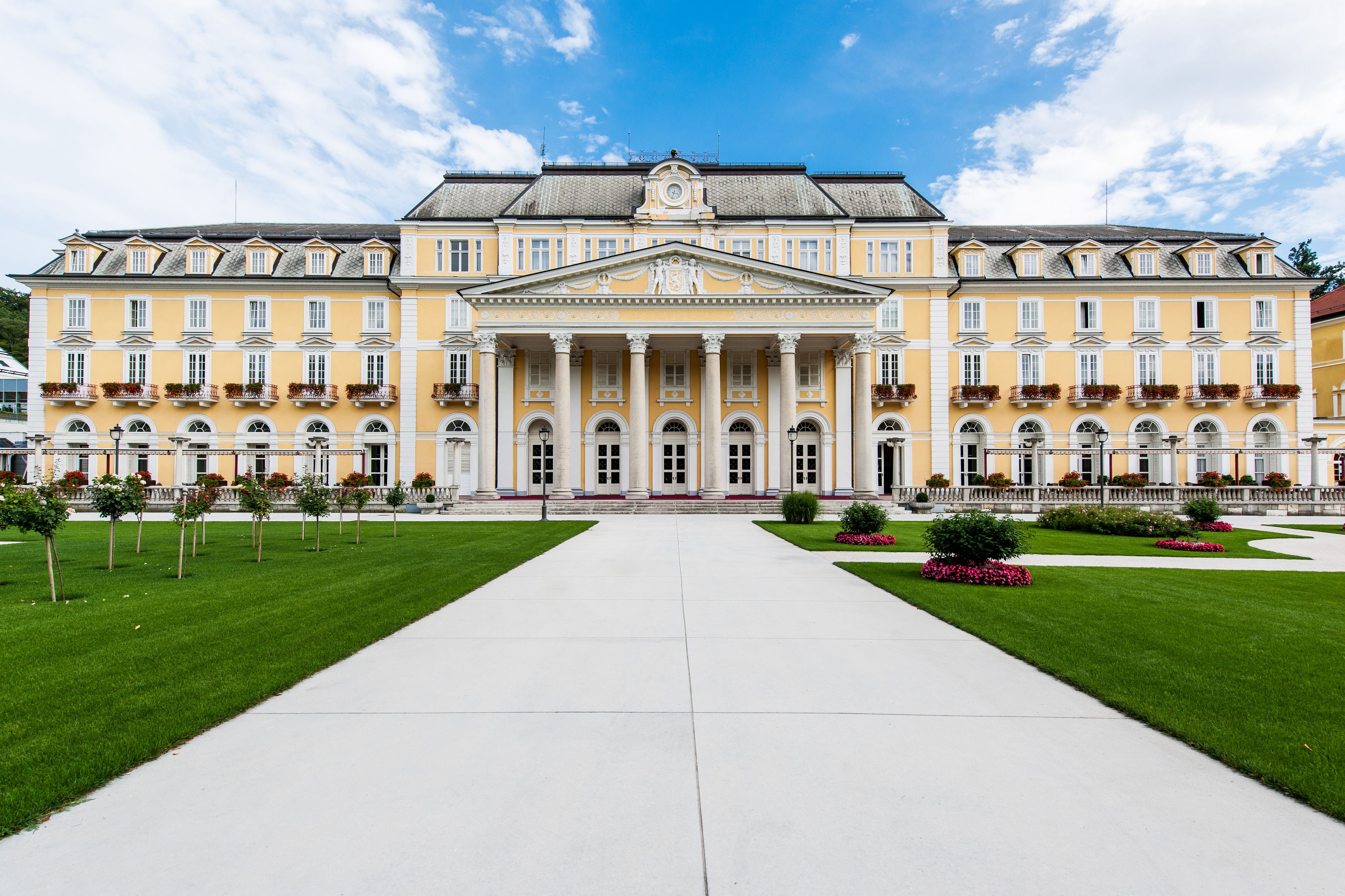 Un edificio grande de estilo clásico, con fachada simétrica, columnas centrales y una entrada formal.