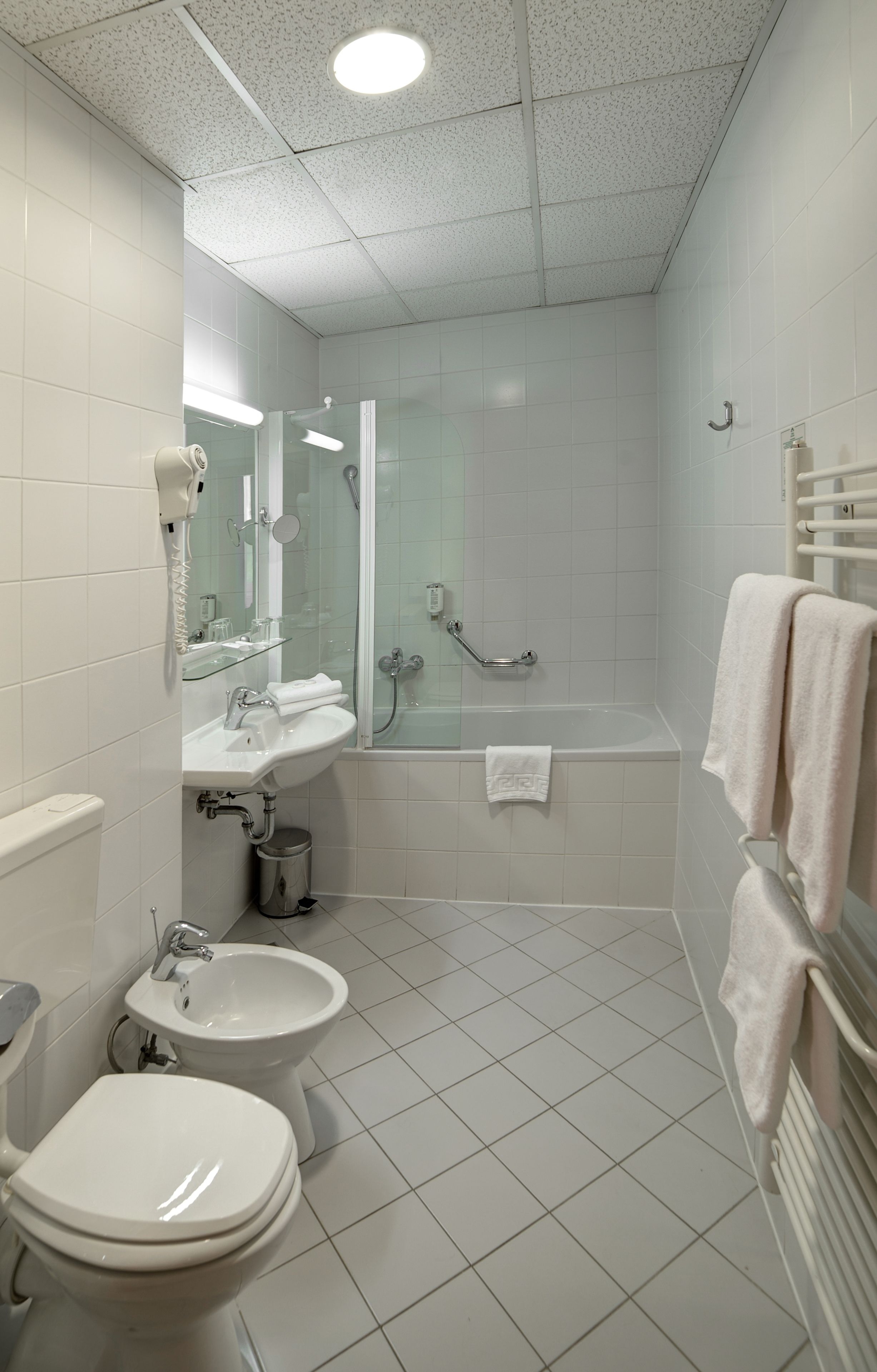 Une salle de bain moderne équipée de toilettes, d’un bidet, d’un lavabo et d’une baignoire.