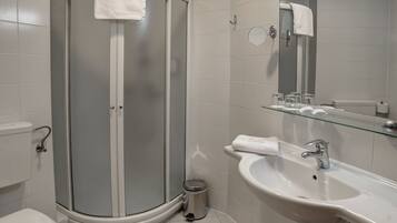 A modern bathroom with a glass-enclosed shower, a white sink, and a toilet.