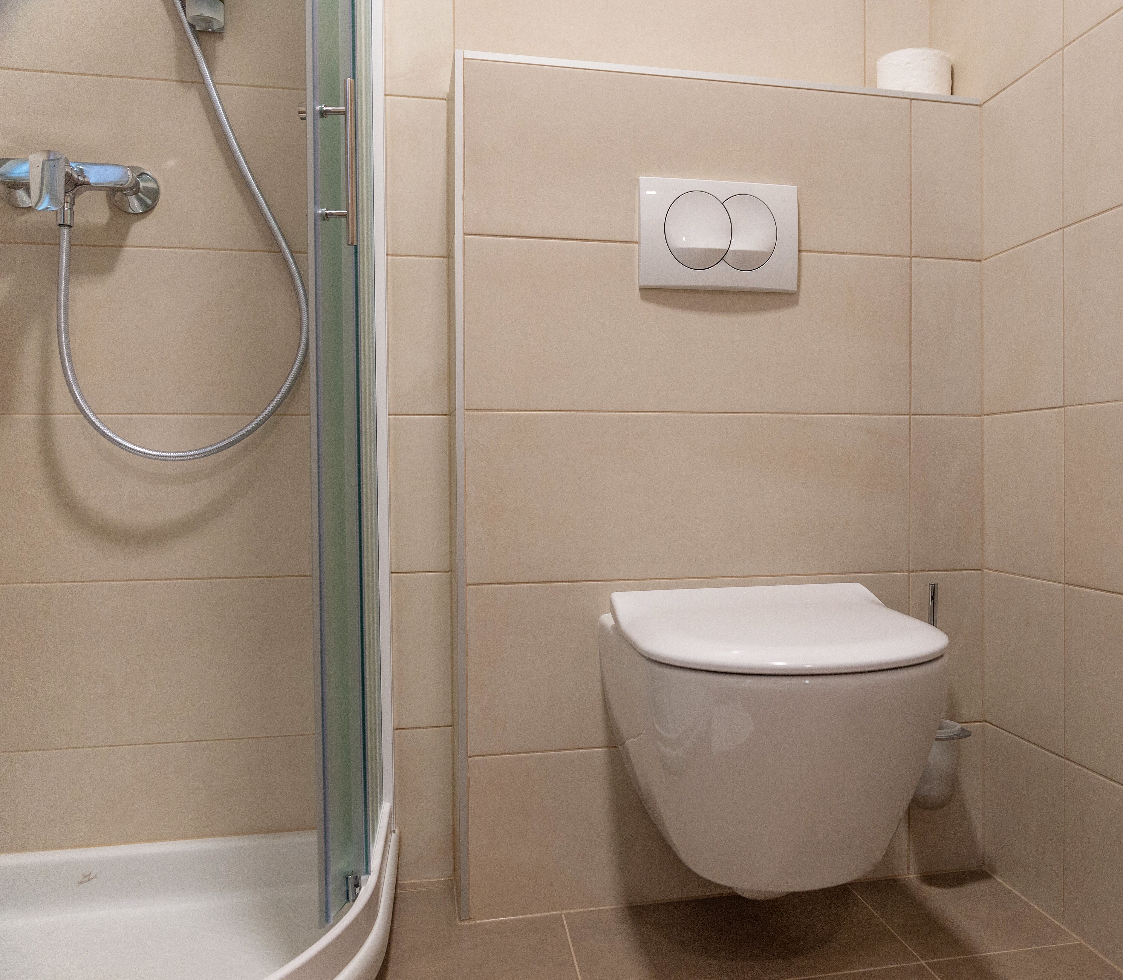 Un baño con ducha, inodoro y un perchero para toallas.