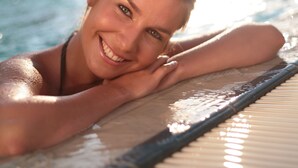 A person relaxing by a poolside with a clear view of the water and a building in the background.