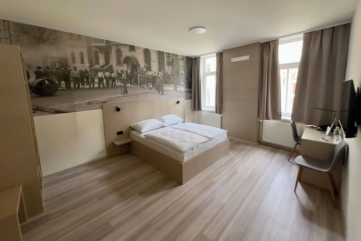 Een moderne hotelkamer met een groot bed, een bureau en een muurschildering.