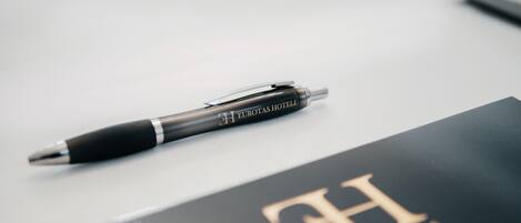 A black pen with gold lettering and a black book with gold lettering.