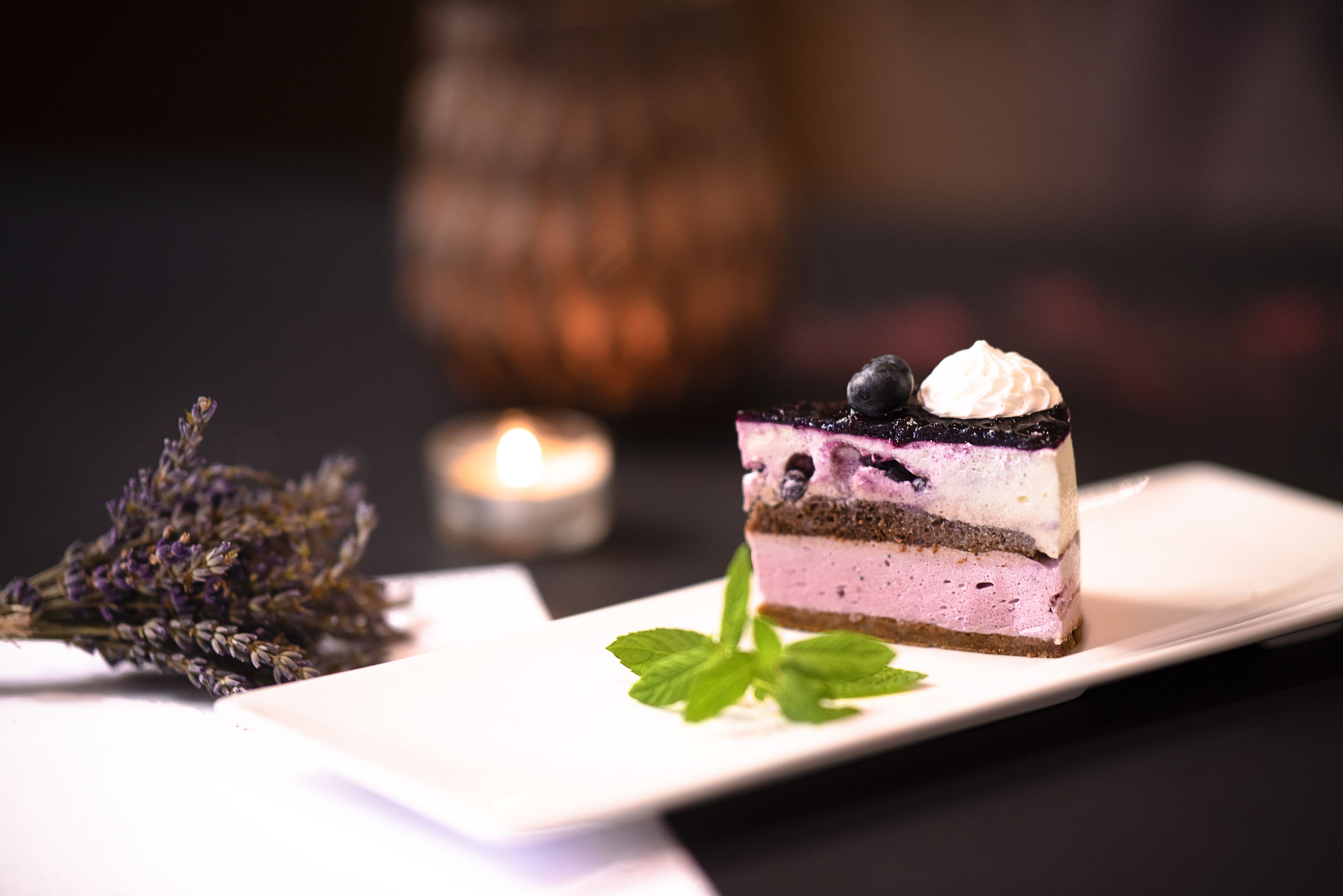 A slice of layered cake on a white plate with a mint leaf garnish.
