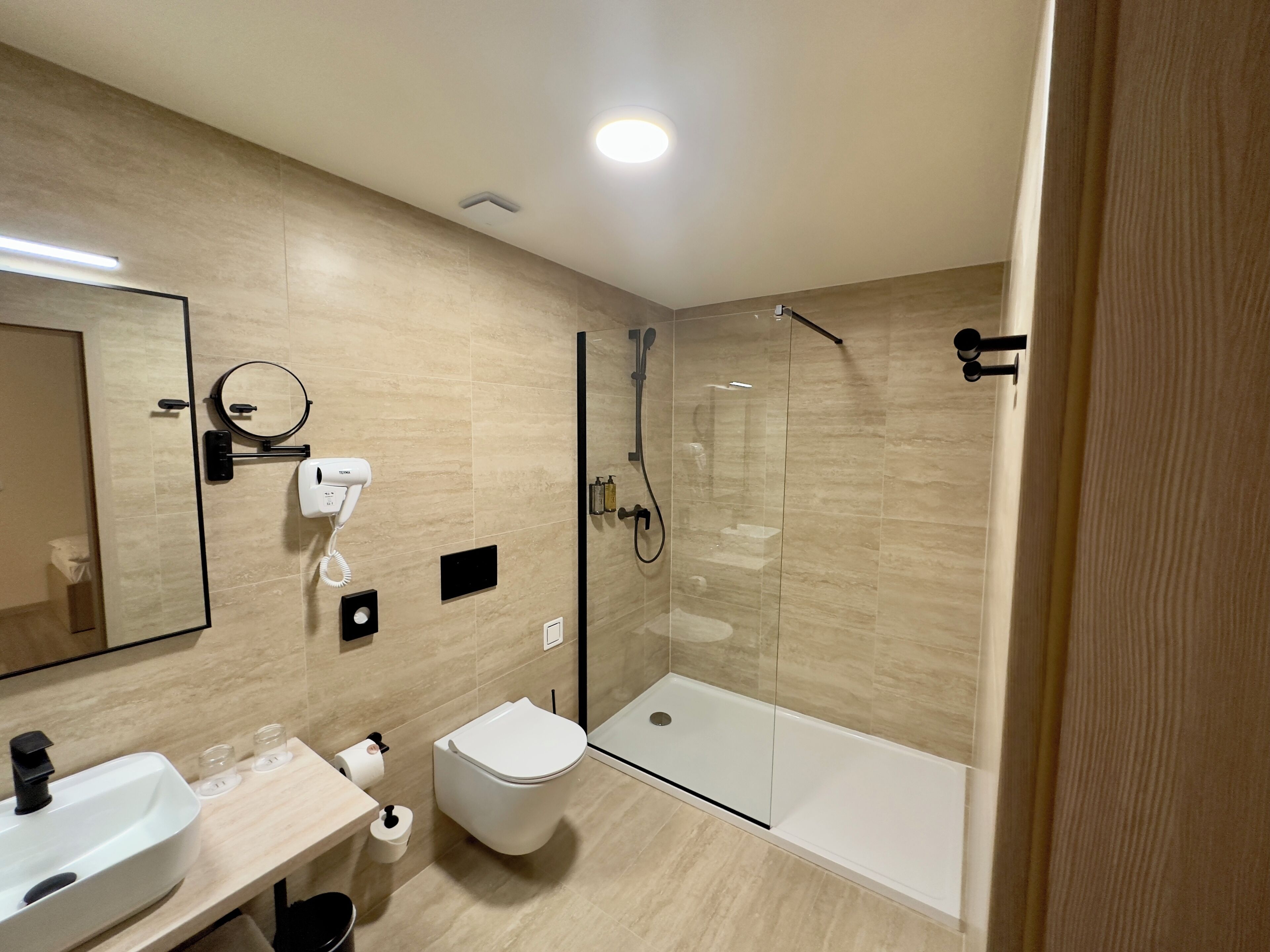 Un baño moderno con inodoro, lavamanos y ducha con cerramiento de vidrio.