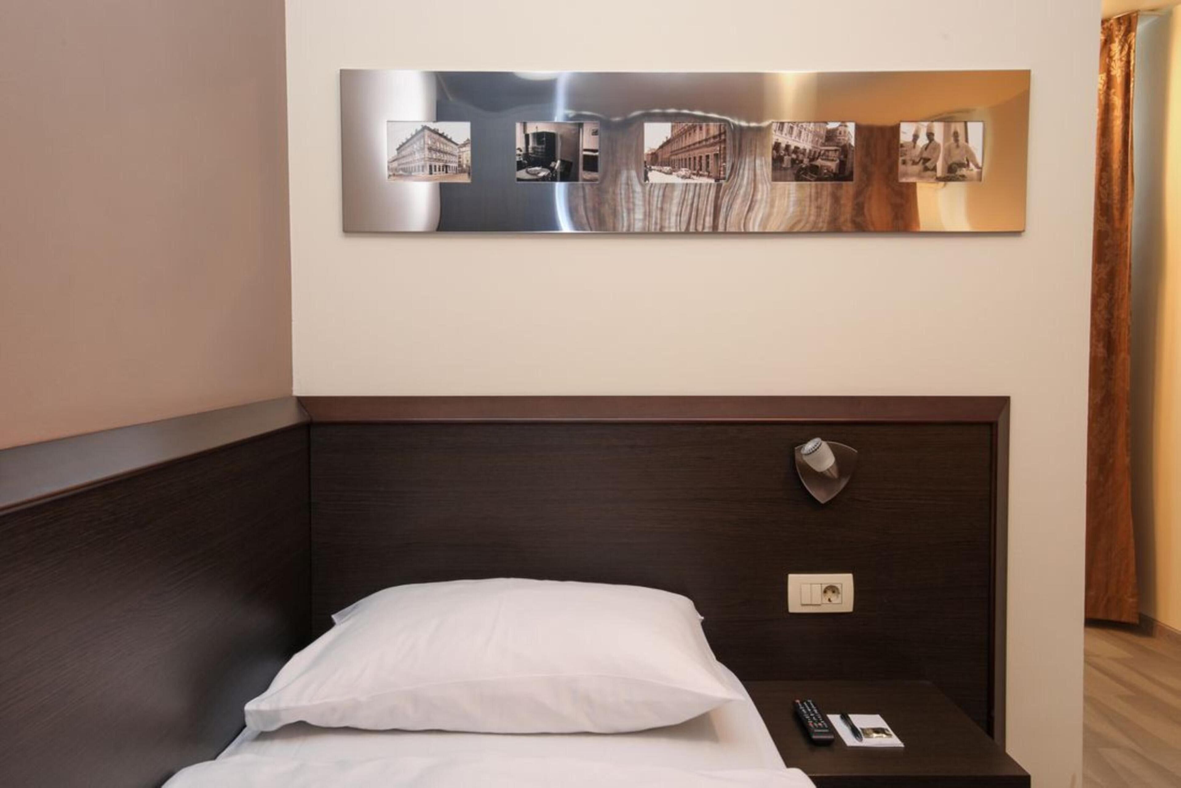 A hotel room with a bed, a nightstand, and a wall-mounted photo collage.