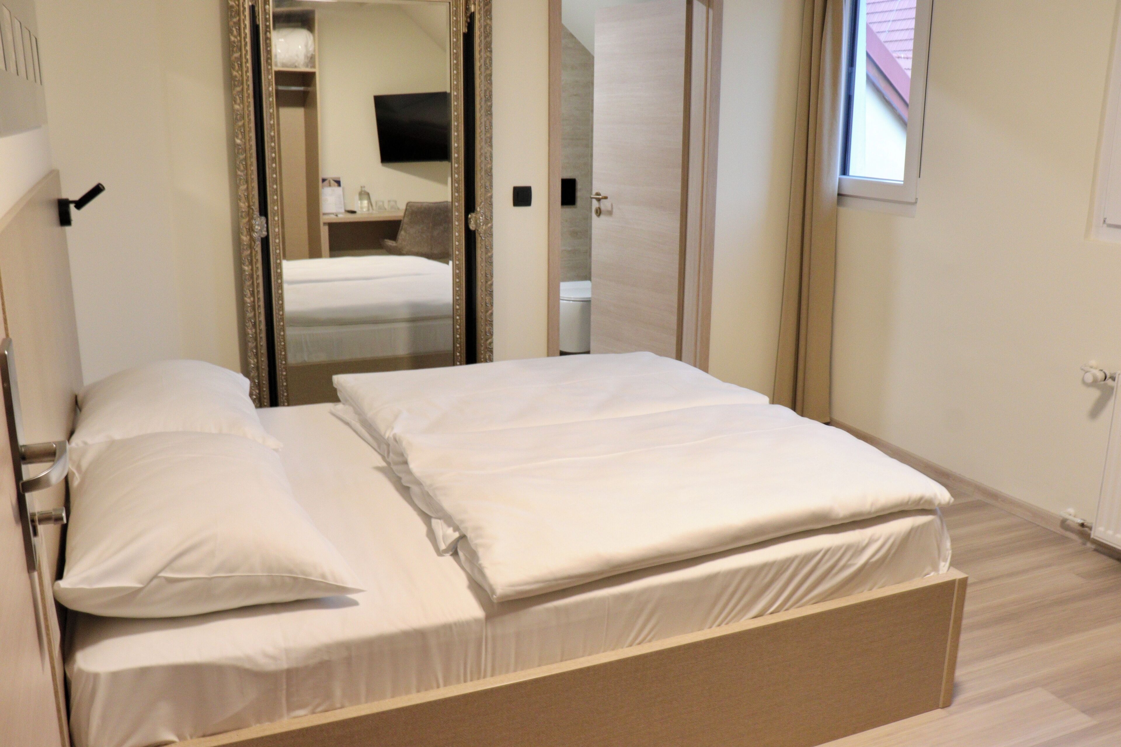 A bedroom with a bed, a mirror, and a wardrobe.