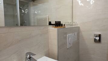 A modern bathroom with a white sink, a toilet, a glass shower enclosure, and a mirror.