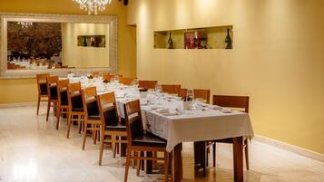 A dining area with a long table set for a meal, surrounded by chairs.