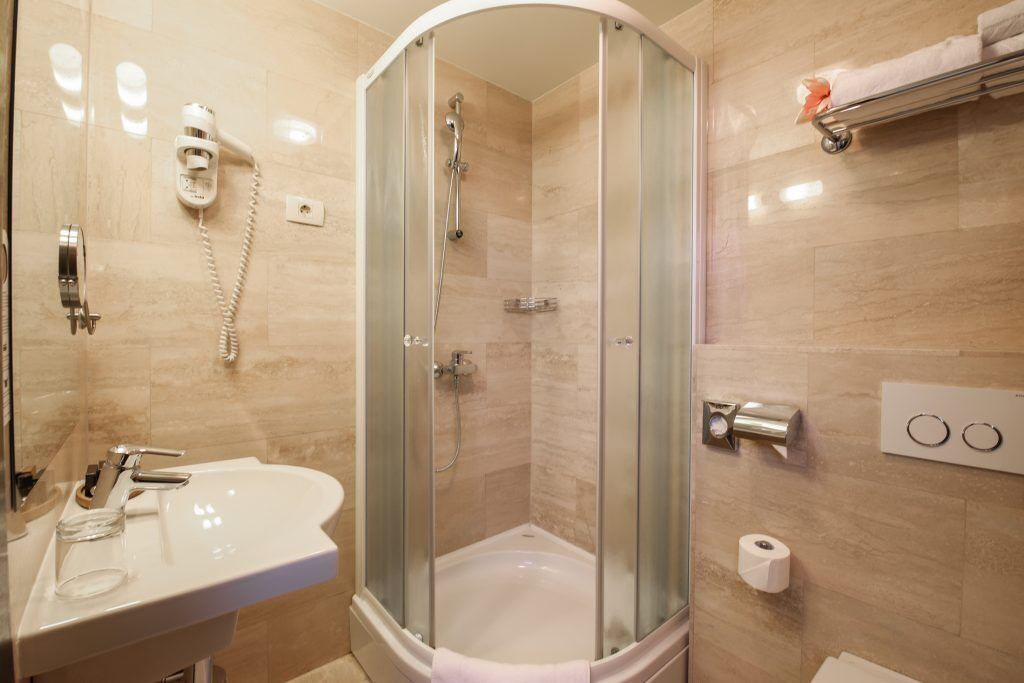 Un baño con ducha de vidrio, lavamanos, inodoro y perchero para toallas.