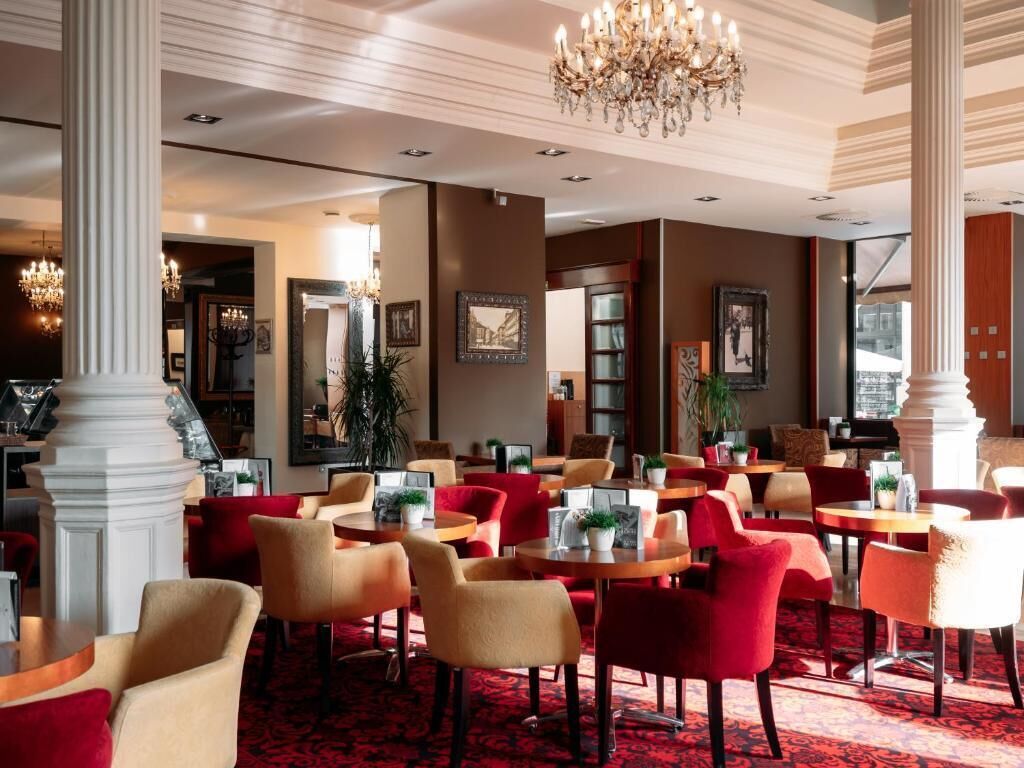 A hotel lobby with multiple seating areas, a chandelier, and framed artwork on the walls.