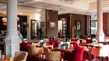 A hotel lobby with multiple seating areas, a chandelier, and framed artwork on the walls.