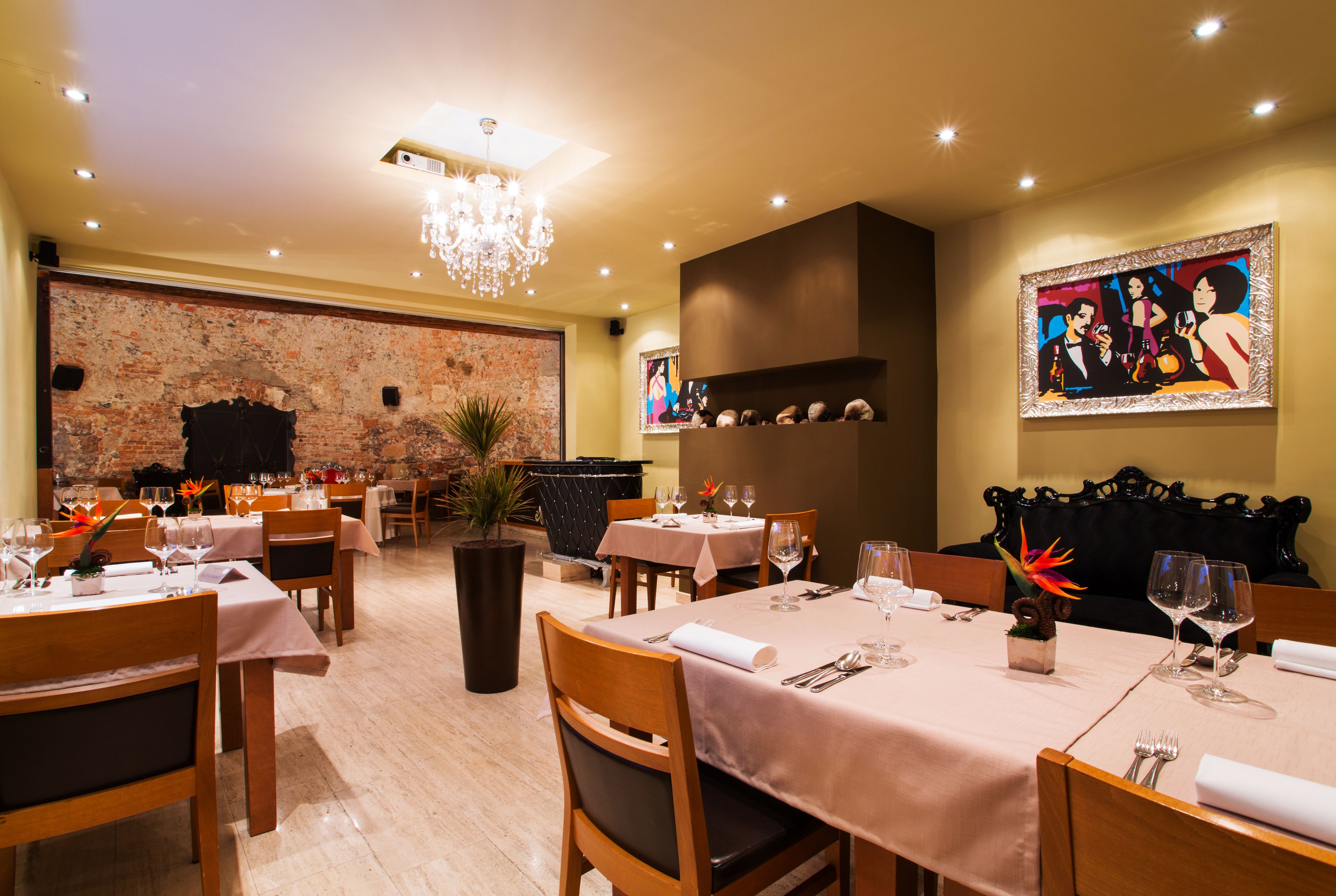 Ein Restaurant mit mehreren Esstischen, einer Deckenleuchte und einer Ziegelwand.