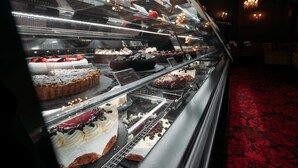 Vitrine de pastelaria com diversos bolos e doces.