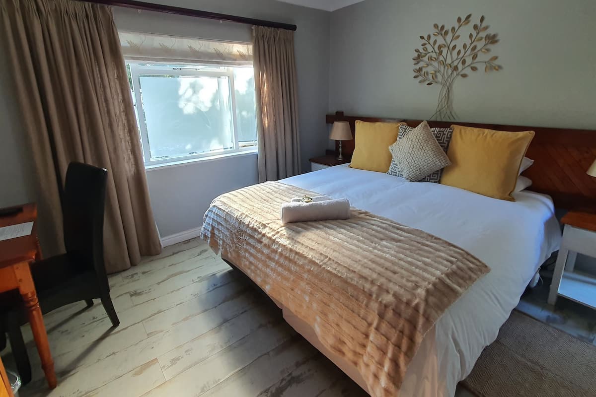 Une chambre d’hôtel avec un grand lit, un bureau et une fenêtre avec des rideaux.