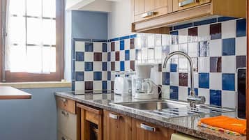 A kitchen with wooden cabinets, a tiled backsplash, a window, and a built-in dishwasher.