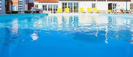 Una piscina al aire libre, sombrillas, sillones reclinables de piscina