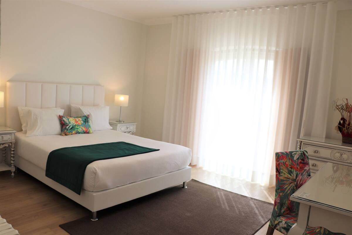 Una habitación de hotel ordenada con una cama grande, un escritorio y una silla.