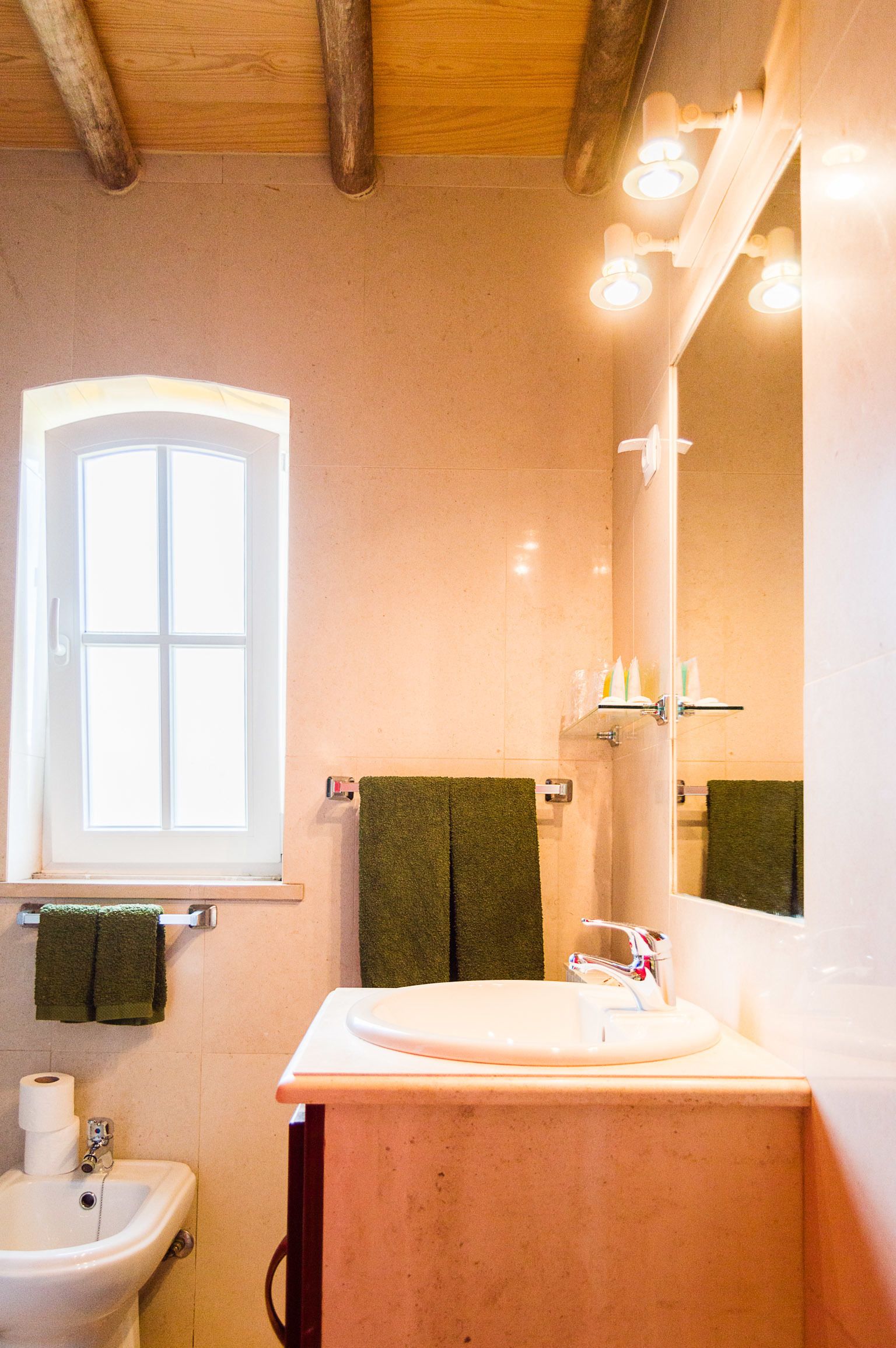 A bathroom with a window, a sink, a mirror, and a towel rack.