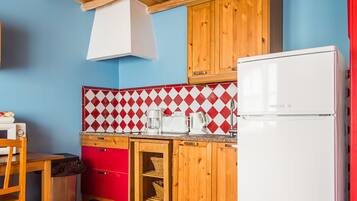 A kitchen with wooden cabinets, a red and white checkered backsplash, a white refrigerator, and a coffee maker.