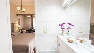 A hotel room with a bed, a bathroom with a sink, and a mirror.