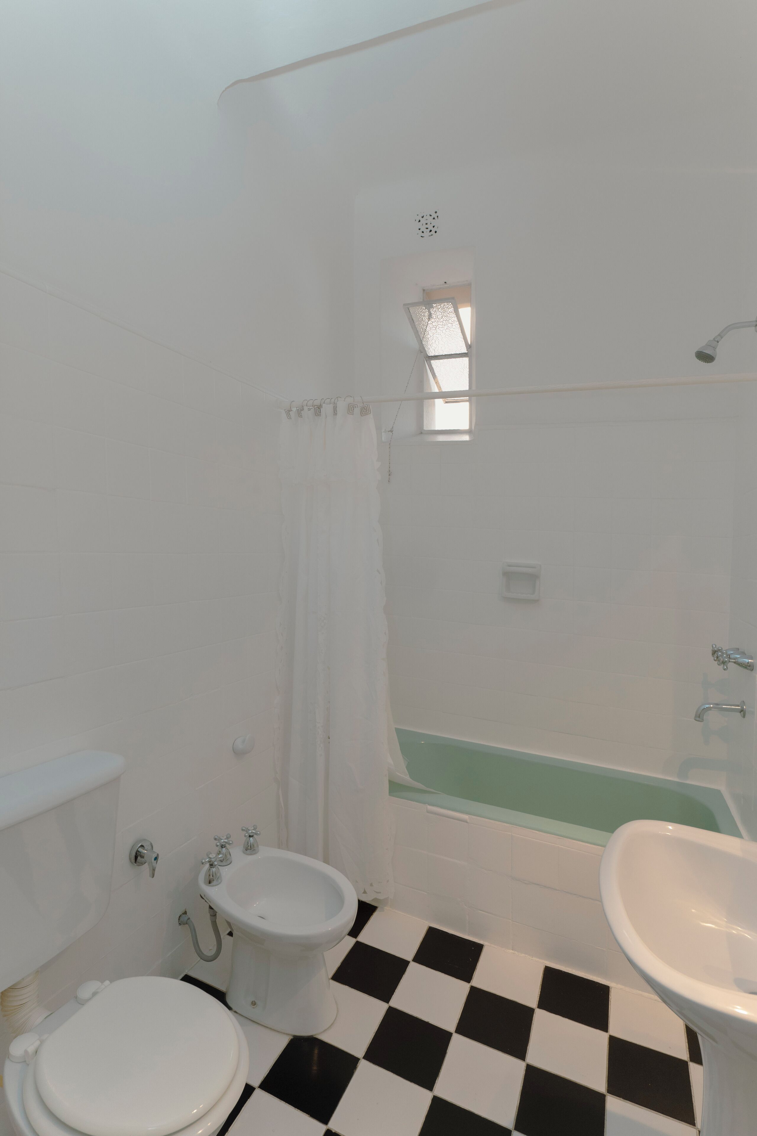 A bathroom with a toilet, bidet, bathtub, and sink.