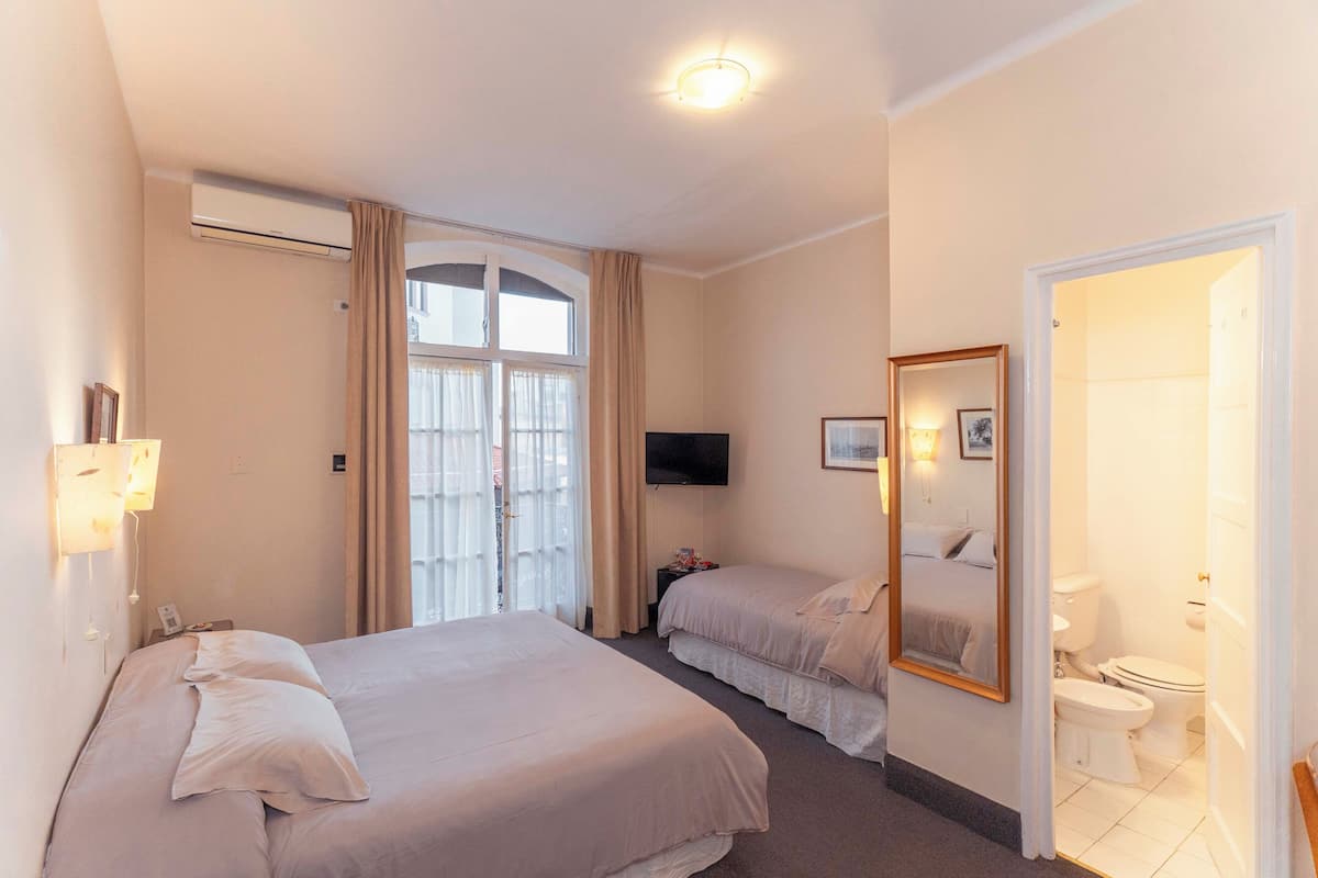 Habitación de hotel con dos camas, televisión, espejo y baño.