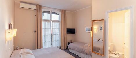 Une chambre d’hôtel avec deux lits, une télévision, un miroir et une salle de bain.