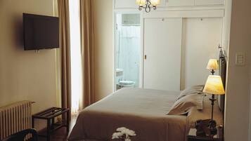 A hotel room with a bed, bedside lamps, a TV, a small table, and a chair.