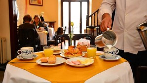 A breakfast table with plates of food, a coffee cup, and a glass of orange juice.