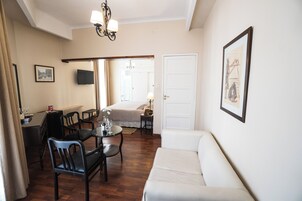 Una habitación de hotel con comedor, sofá, televisión y cama.
