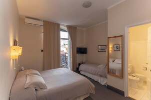 Habitación de hotel con dos camas, televisión, espejo y baño.
