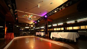 Un restaurante con pista de baile, mesas y escenario.
