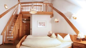 Un dormitorio con una escalera de madera, una cama con ropa de cama blanca y una mesita de noche con lámpara.