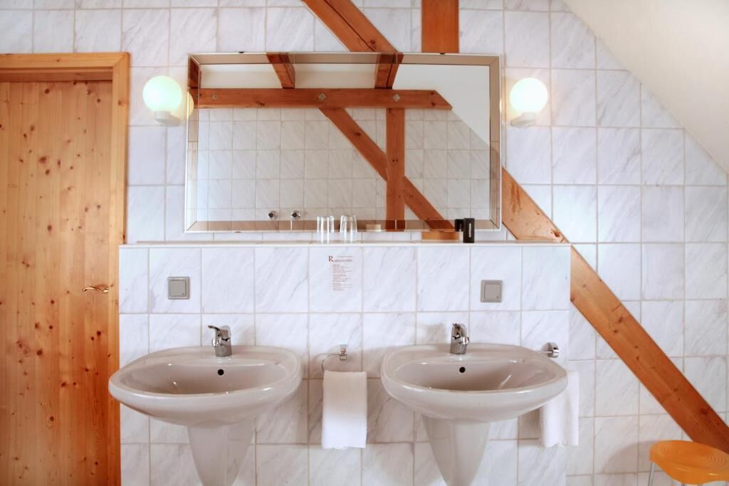 A bathroom with two sinks, a wooden-framed mirror, and a white tiled wall.