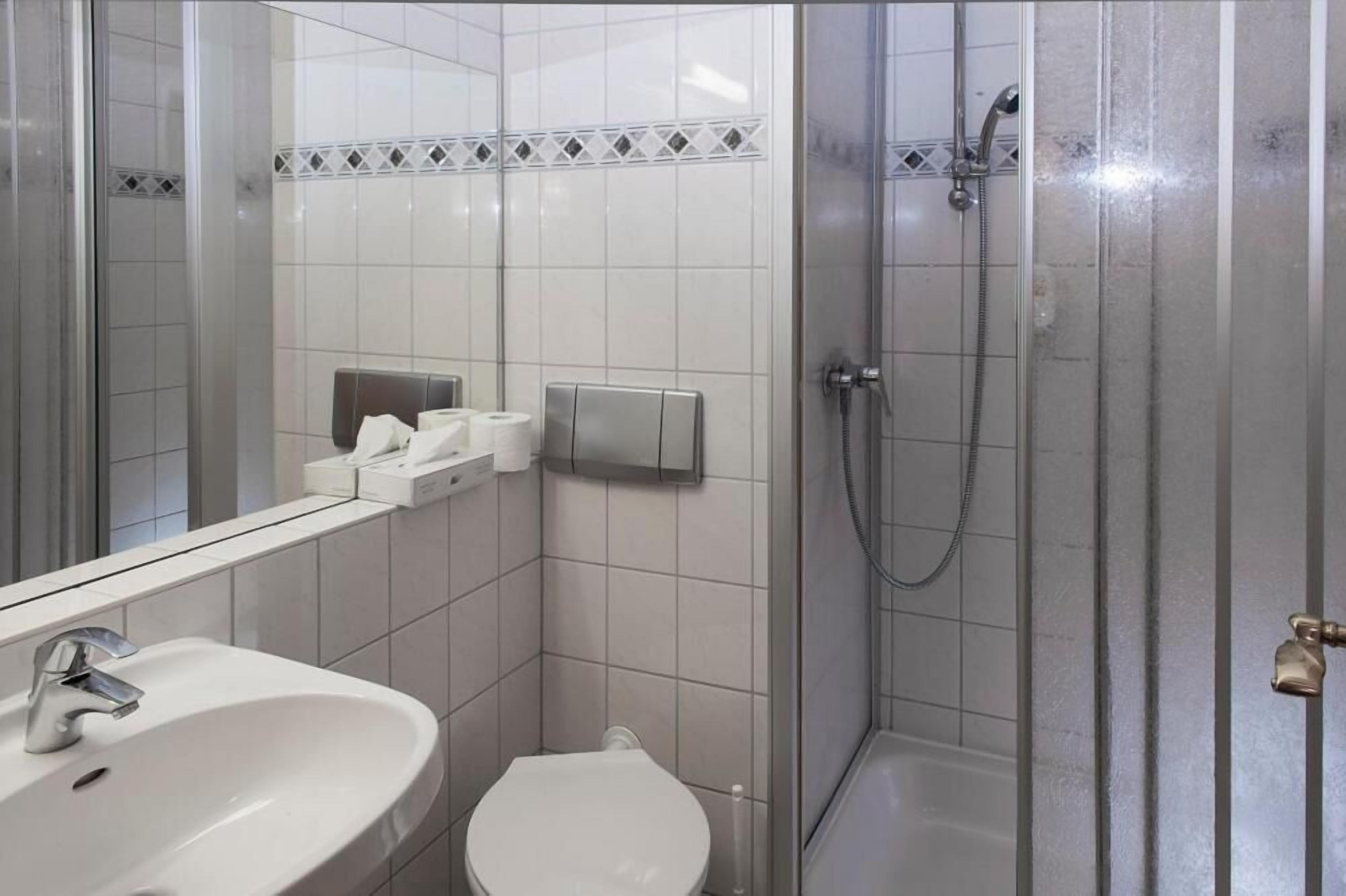 A bathroom with a white sink, toilet, and a glass-enclosed shower area.