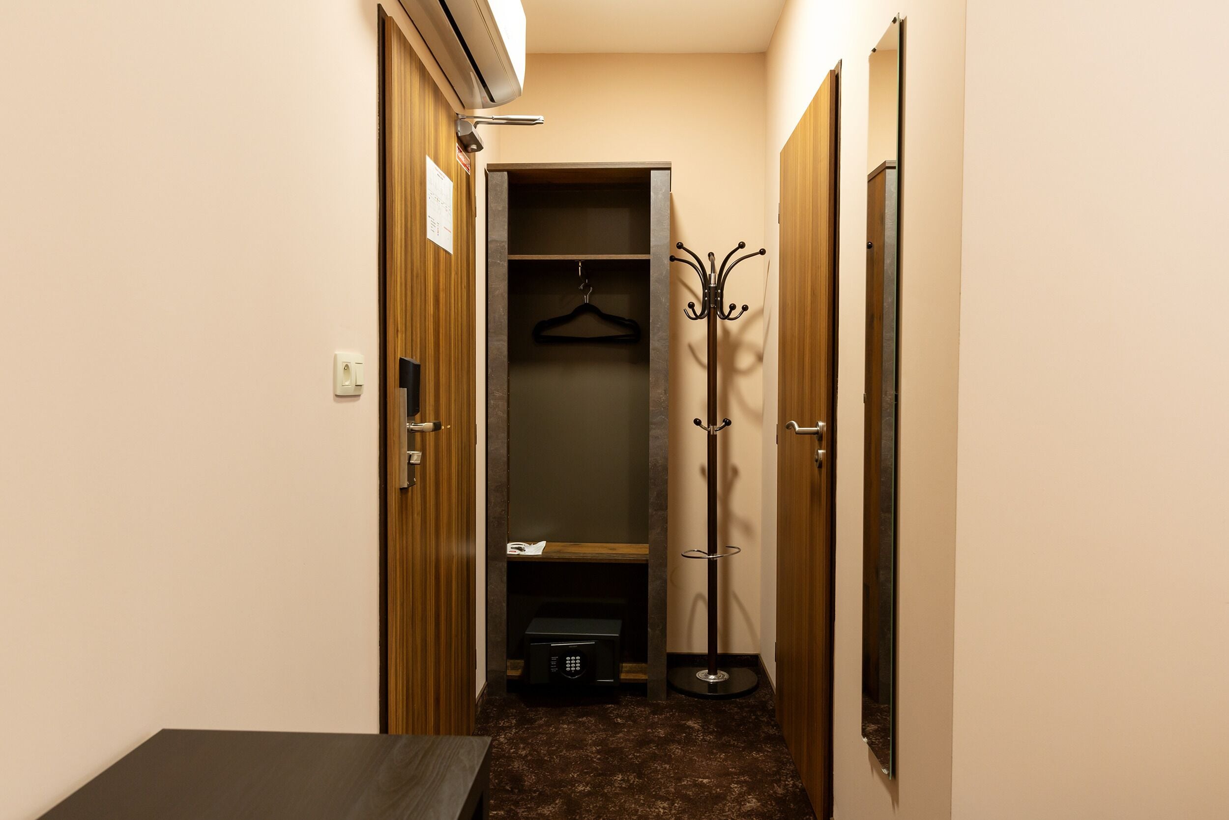 A narrow hallway with a coat rack, a small table, and a wardrobe.