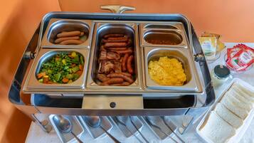 Un buffet proposant une variété de plats, notamment des saucisses, des légumes et de la purée de pommes de terre.