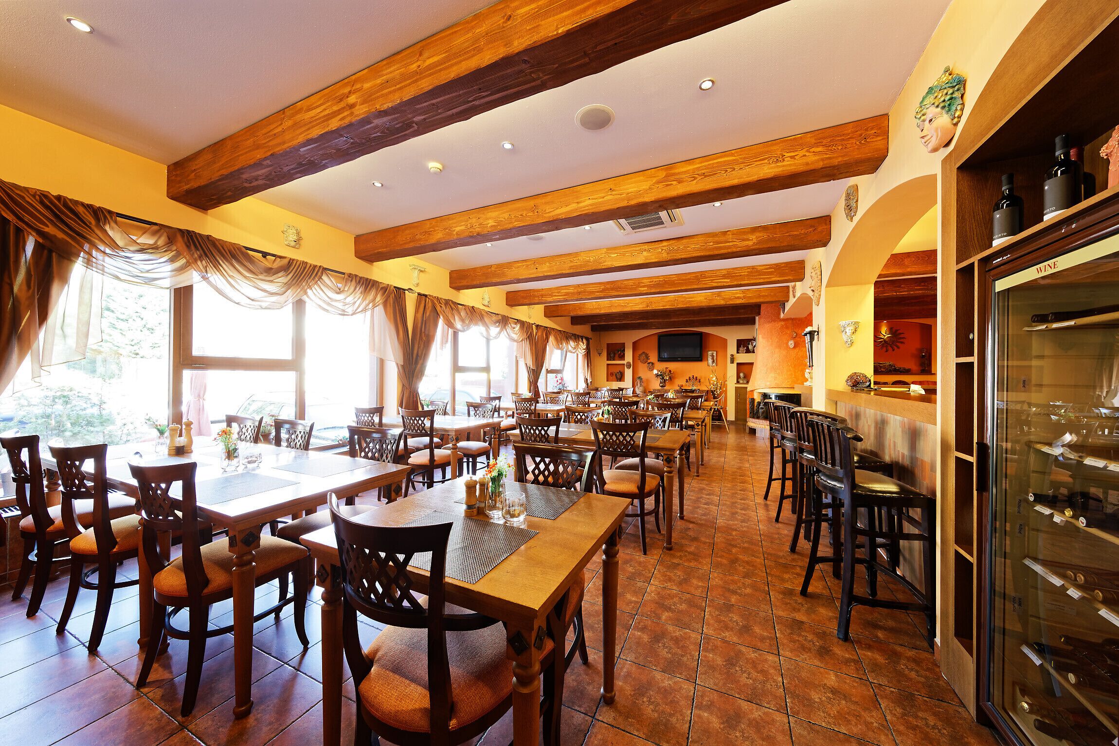 Um restaurante espaçoso com vigas de madeira, amplas janelas e um refrigerador de vinhos.