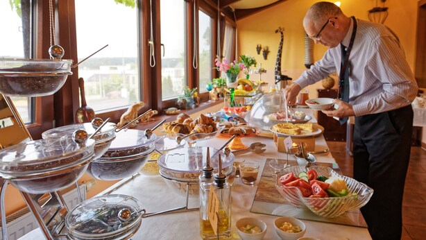 Montaje de bufé con diversas opciones de comida y una persona sirviendo.