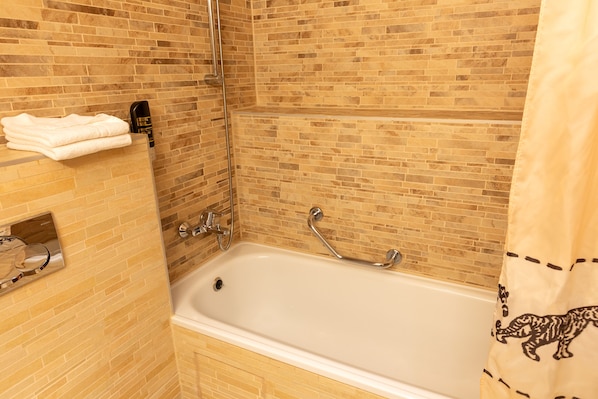 Un baño con bañera, toallero y cabezal de ducha.