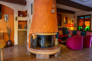 Tunnelmallinen olohuone, jonka keskipisteenä on takka, ja jossa on myös sohva ja sohvapöytä.