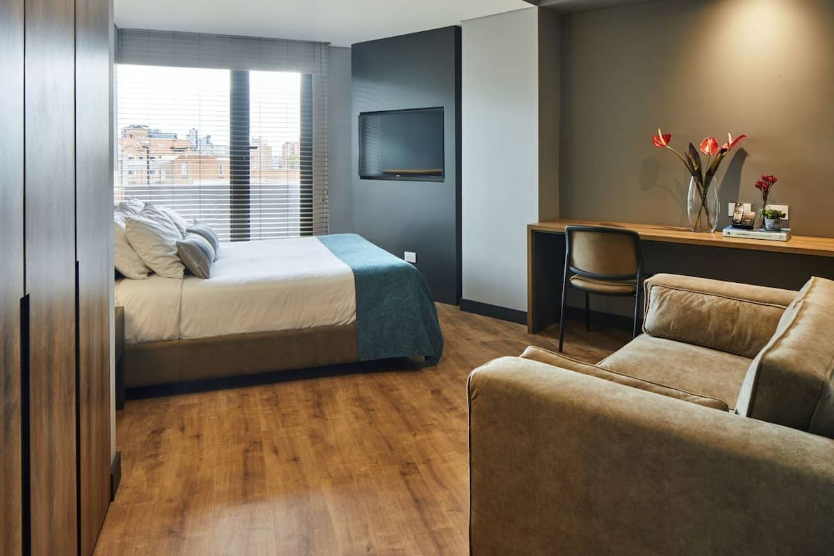 Quarto moderno com uma cama, uma escrivaninha e um sofá.