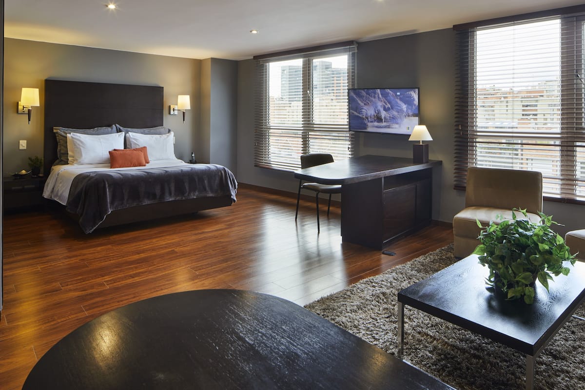 Quarto de hotel moderno com uma cama grande, uma mesa, uma cadeira e uma televisão.