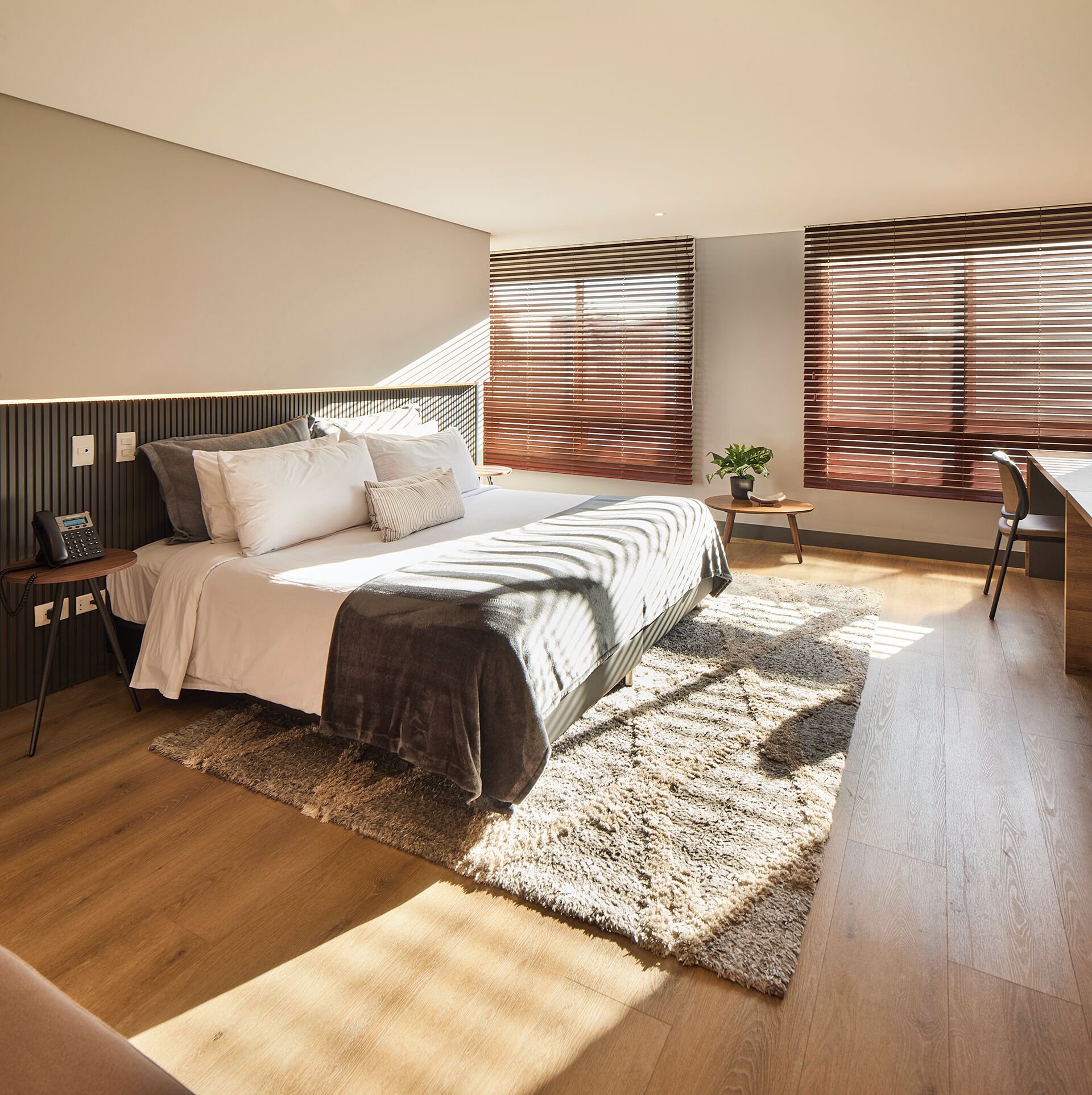 Une chambre à coucher moderne avec un lit, une table de chevet et un petit espace bureau.