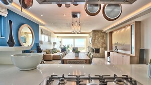 A modern kitchen with a gas stove, a large bowl, and a dining area with a stone wall and large windows. - Ocean View House (Cape Town)